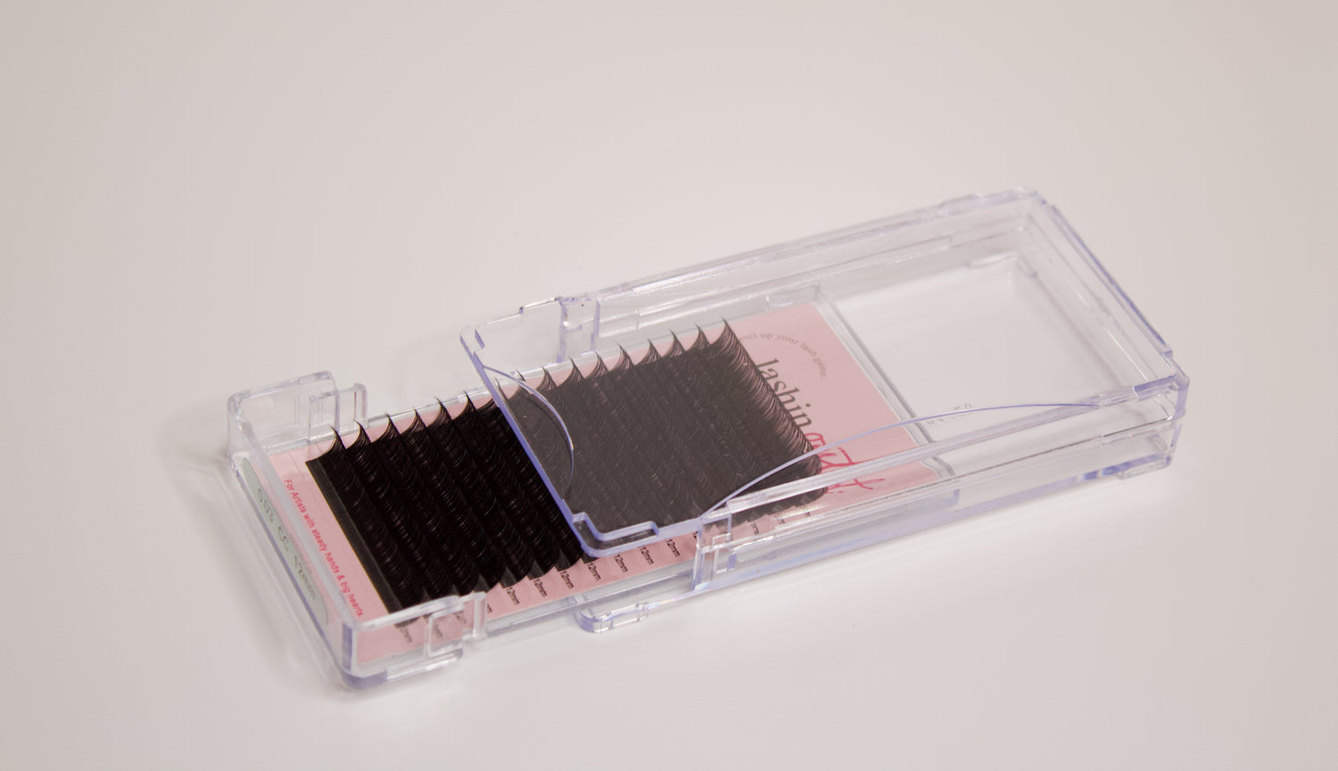 Clear tray with volume lash extensions inside. The drawer is half open and the rows of lashes are clearly seen on the sheet.