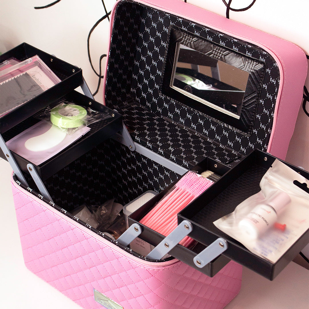 Lash training kit is shown. The case is pink on the outside and black on the inside. Products are shown in the kit. 