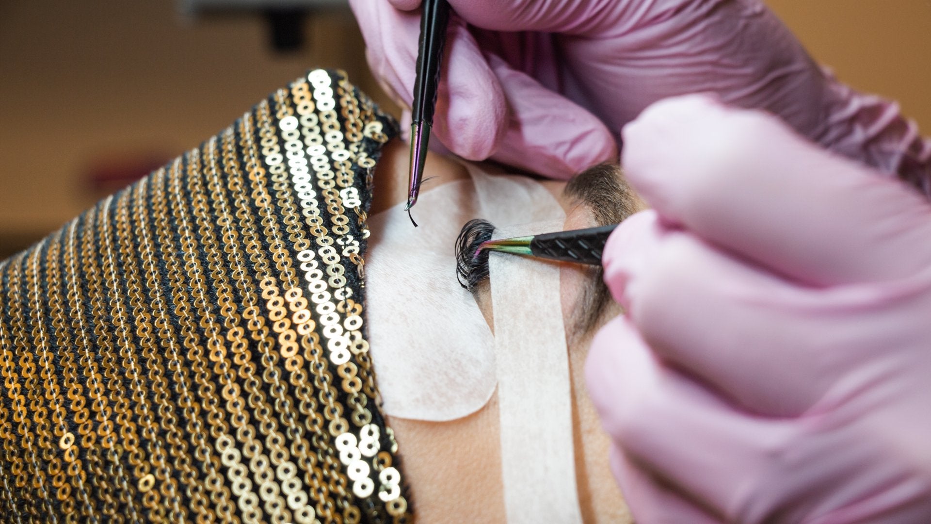 A lash artist is applying eyelash extensions to a person. 