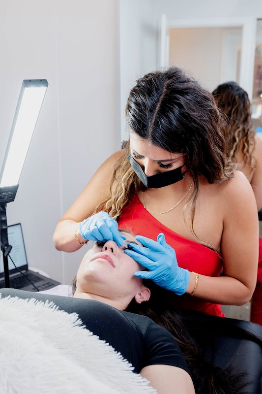 A professional lash artist applying lash extensions salon environment.