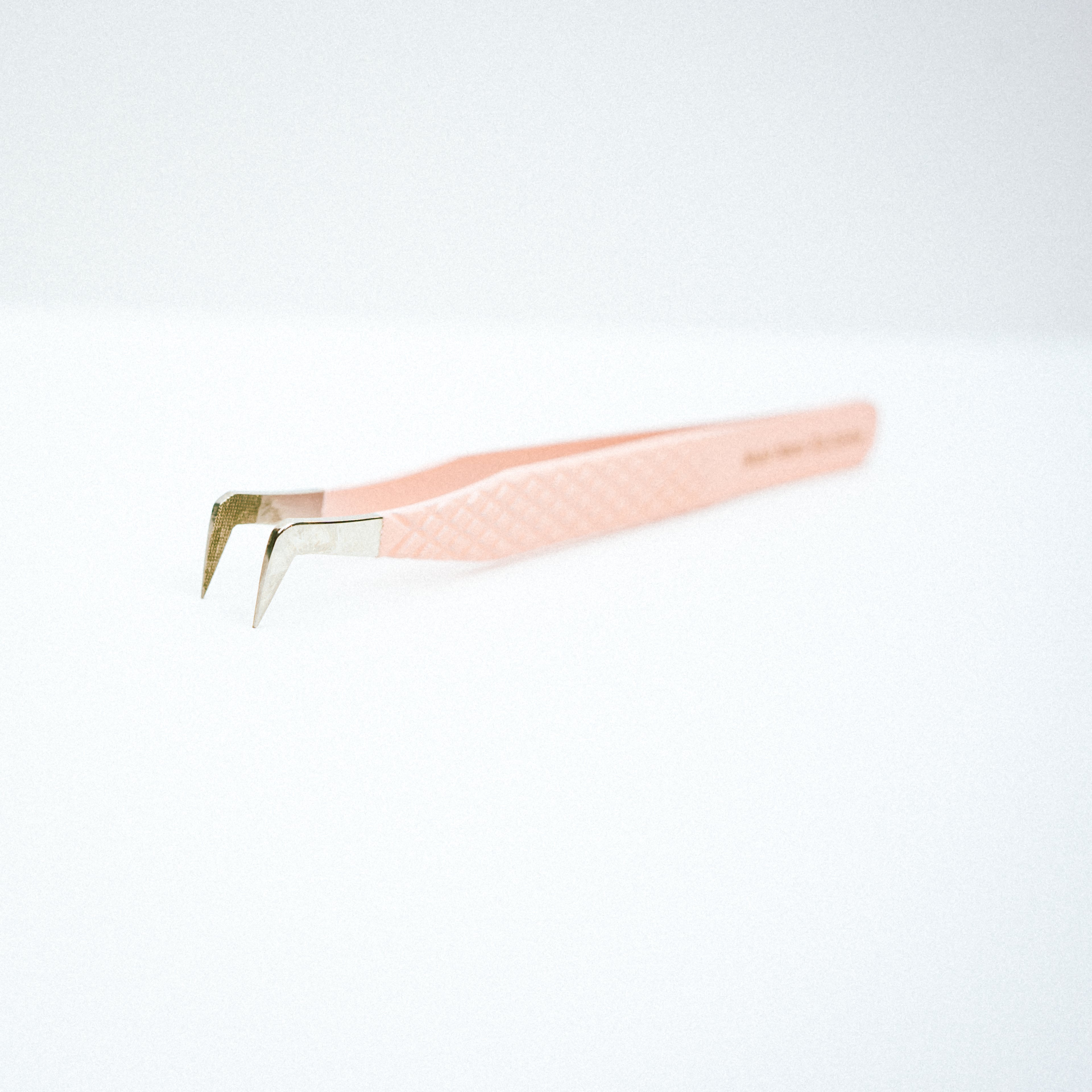 Front view of the Essential Blush Nano Tip Lash Tweezer. The tips of the tweezer are at  90 degree angle and pointing down. 