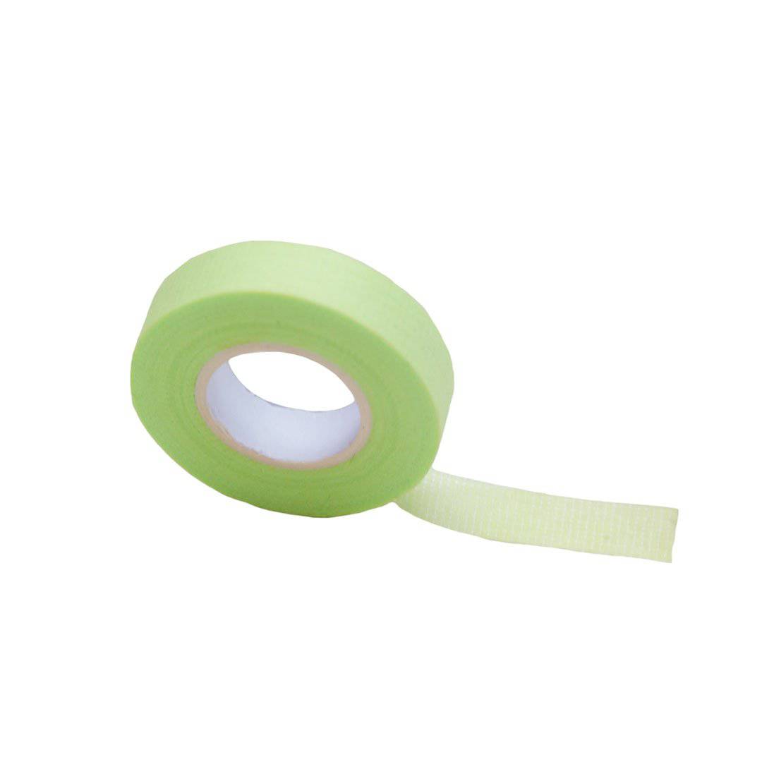 A roll of green lash tape is upright with a small strip of tape pulled off. 