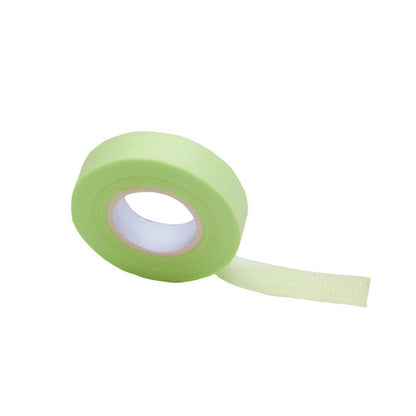 A roll of green lash tape is upright with a small strip of tape pulled off. 