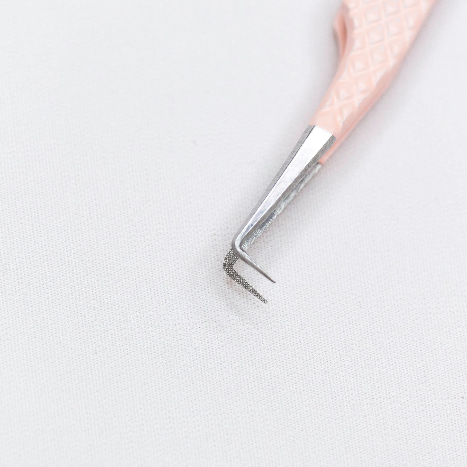 Close up of the tips of the Rosé 90º Blush Nano Tip Lash Tweezer. The tips are thin and at a 90 degree angle. 