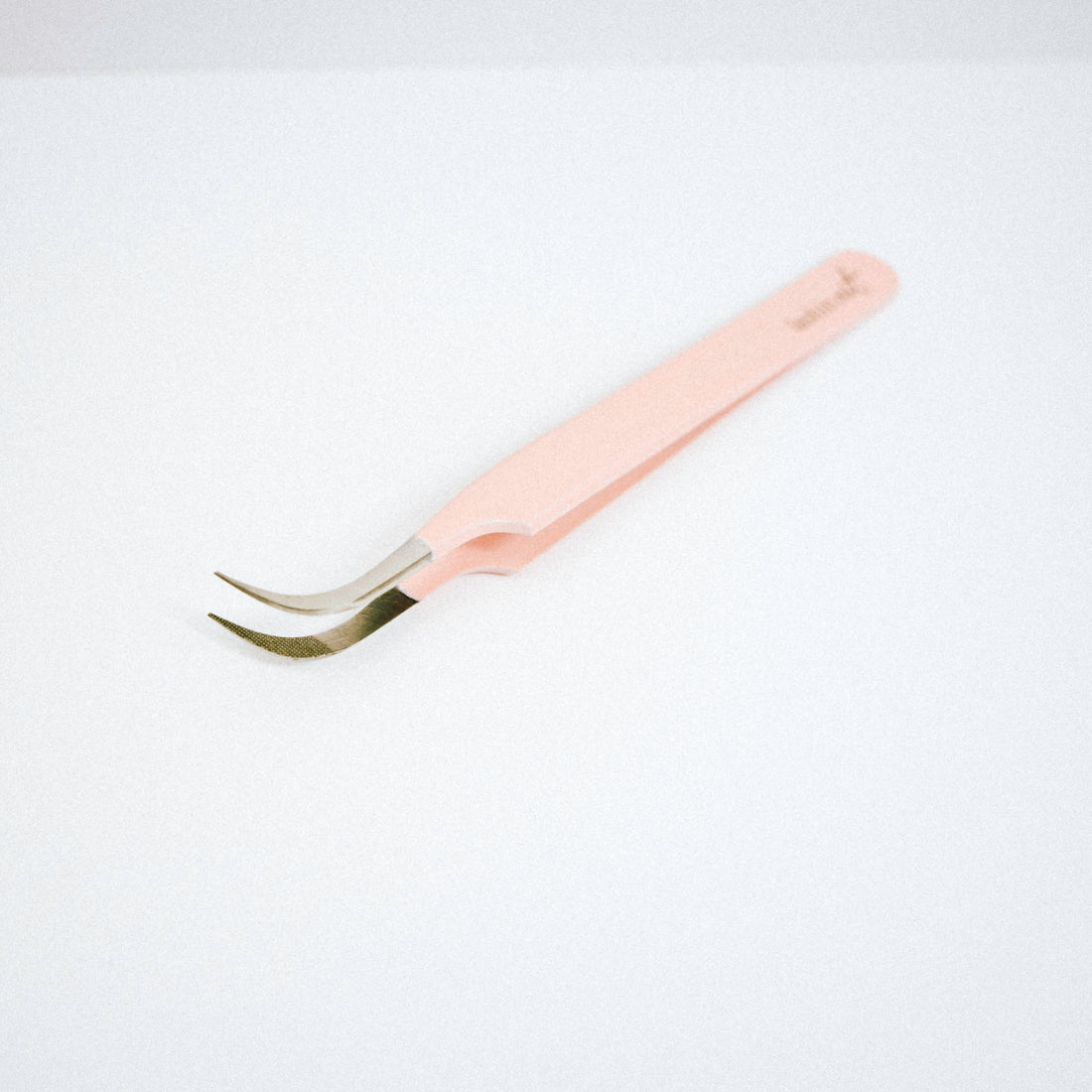 Top view of the Vetus Curved Blush Nano Tip Lash Tweezer. The tweezer is on the side with the curved tips facing upward. 