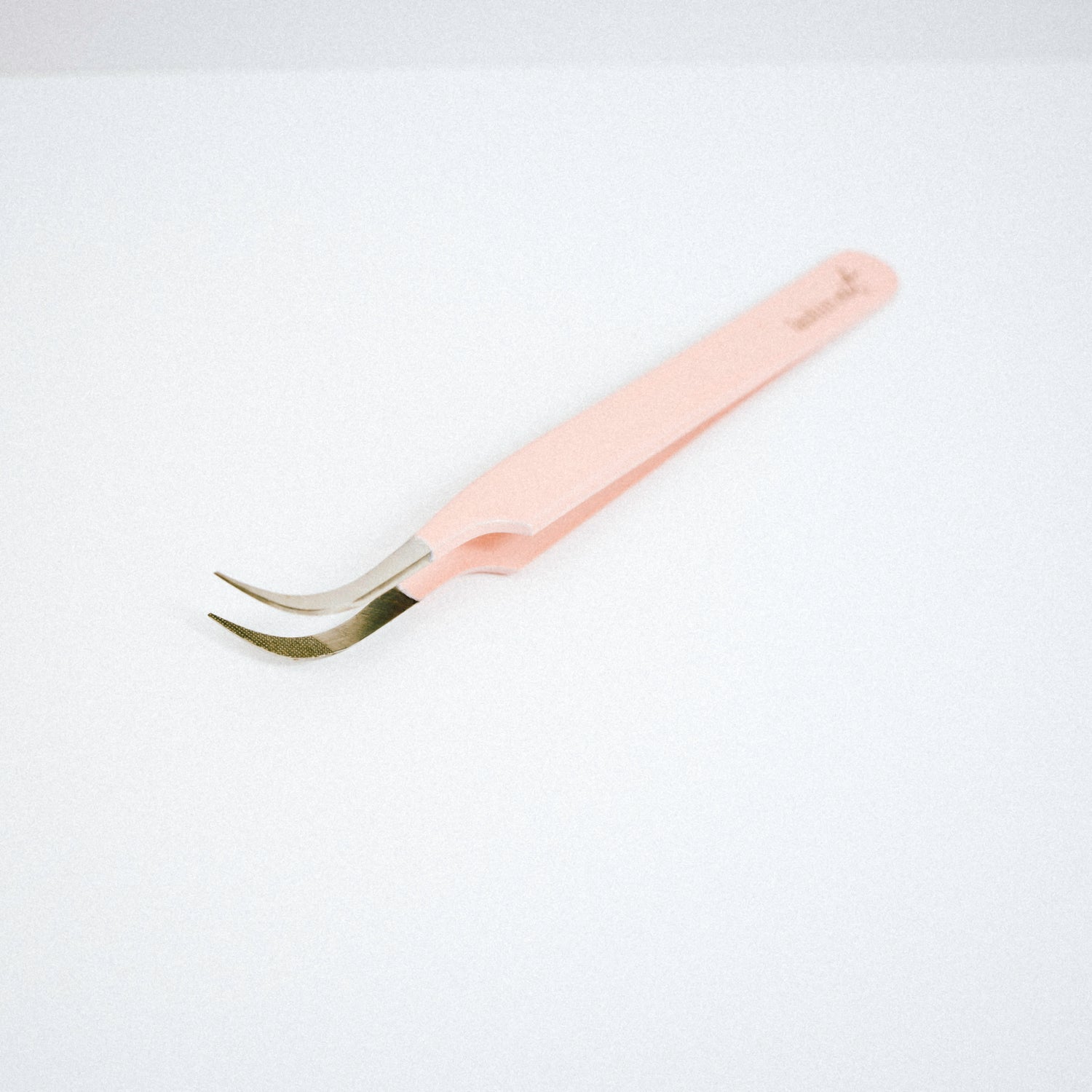 Top view of the Vetus Curved Blush Nano Tip Lash Tweezer. The tweezer is on the side with the curved tips facing upward. 