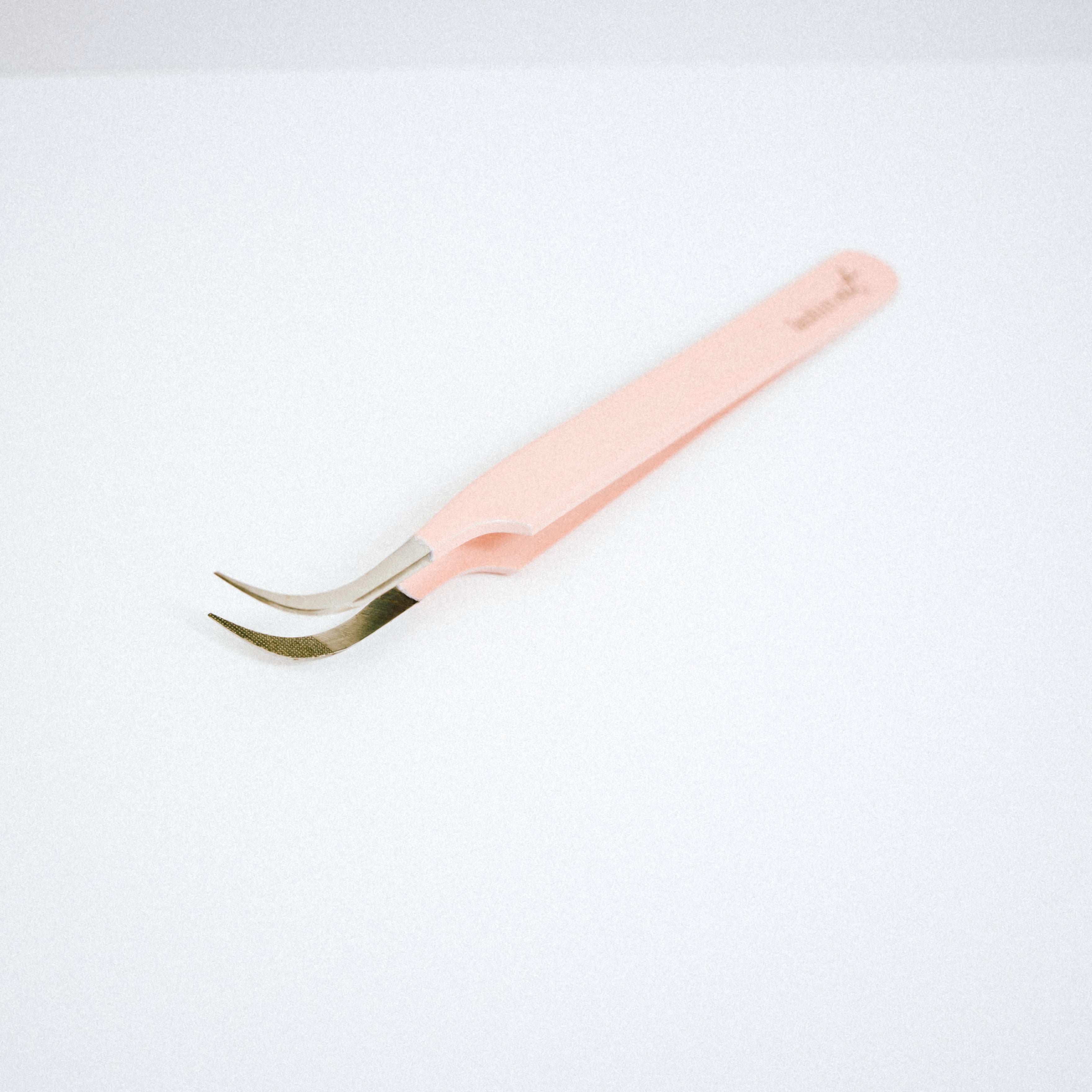 Top view of the Vetus Curved Blush Nano Tip Lash Tweezer. The tweezer is on the side with the curved tips facing upward. 