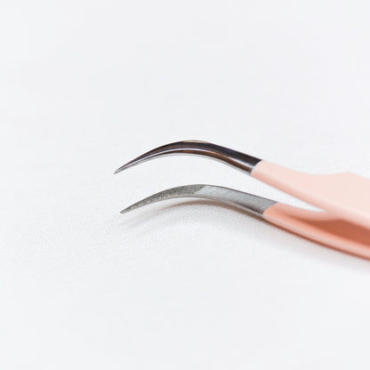 Close up view of the tips of the Vetus Curved Blush Nano Tip Lash tweezer. 